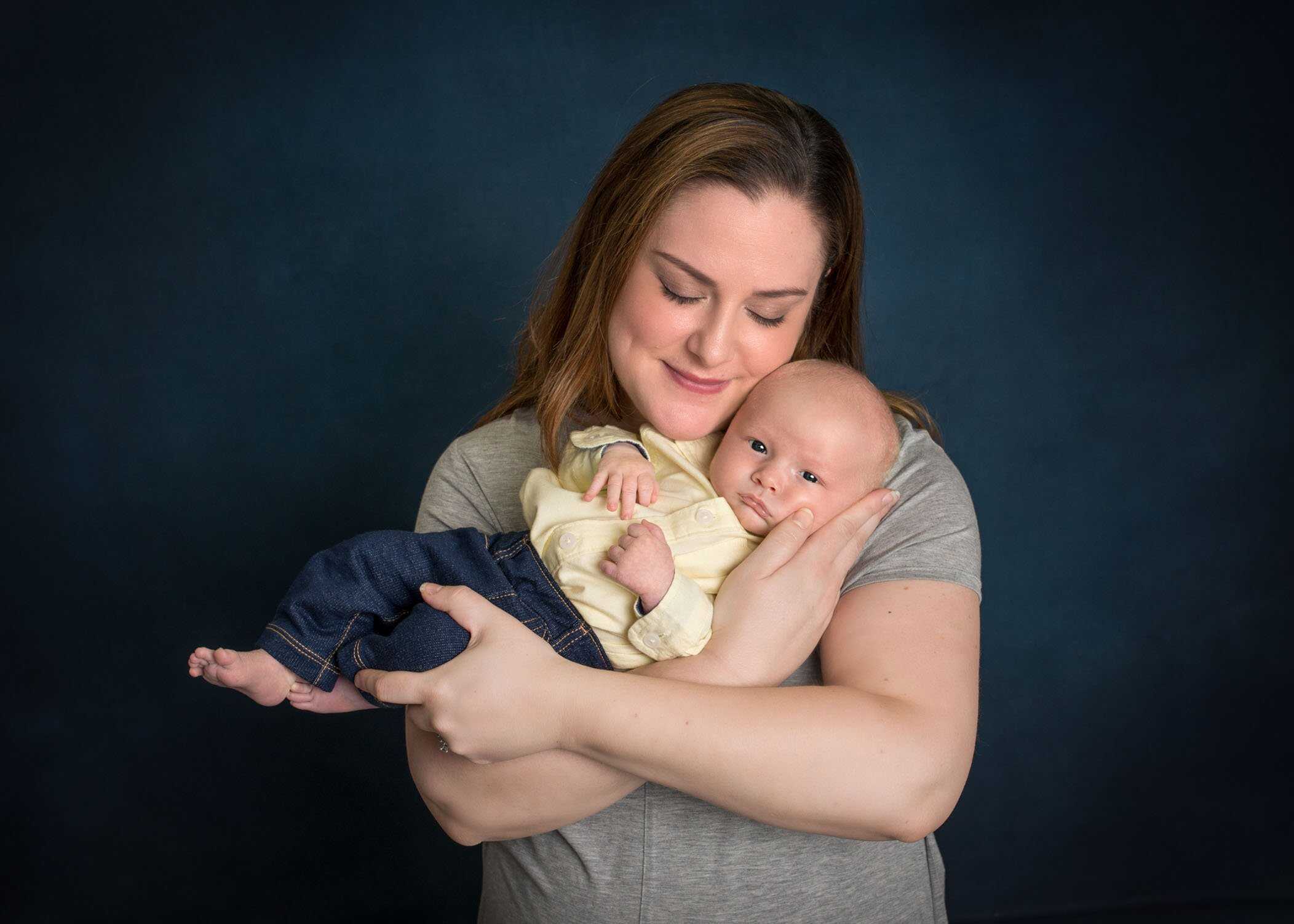 Mom holding her newborn son with her cheek resting on his head