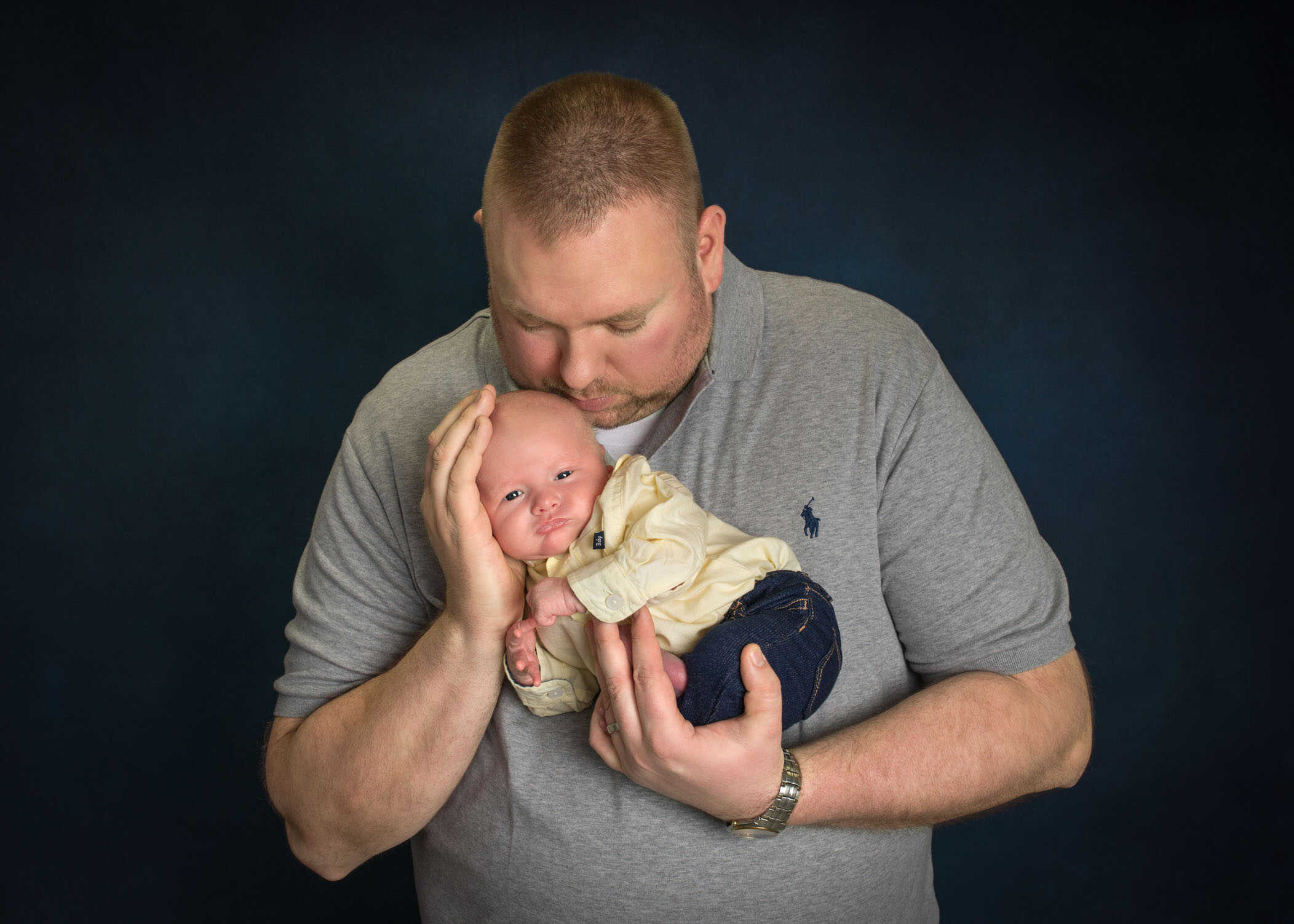 Dad holding his tiny newborn son in his hands and kissing his head
