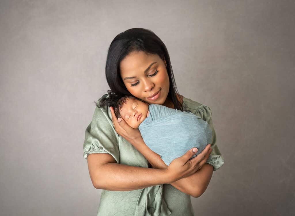 Mother cradling newborn in sage wrap during awake newborn photo session