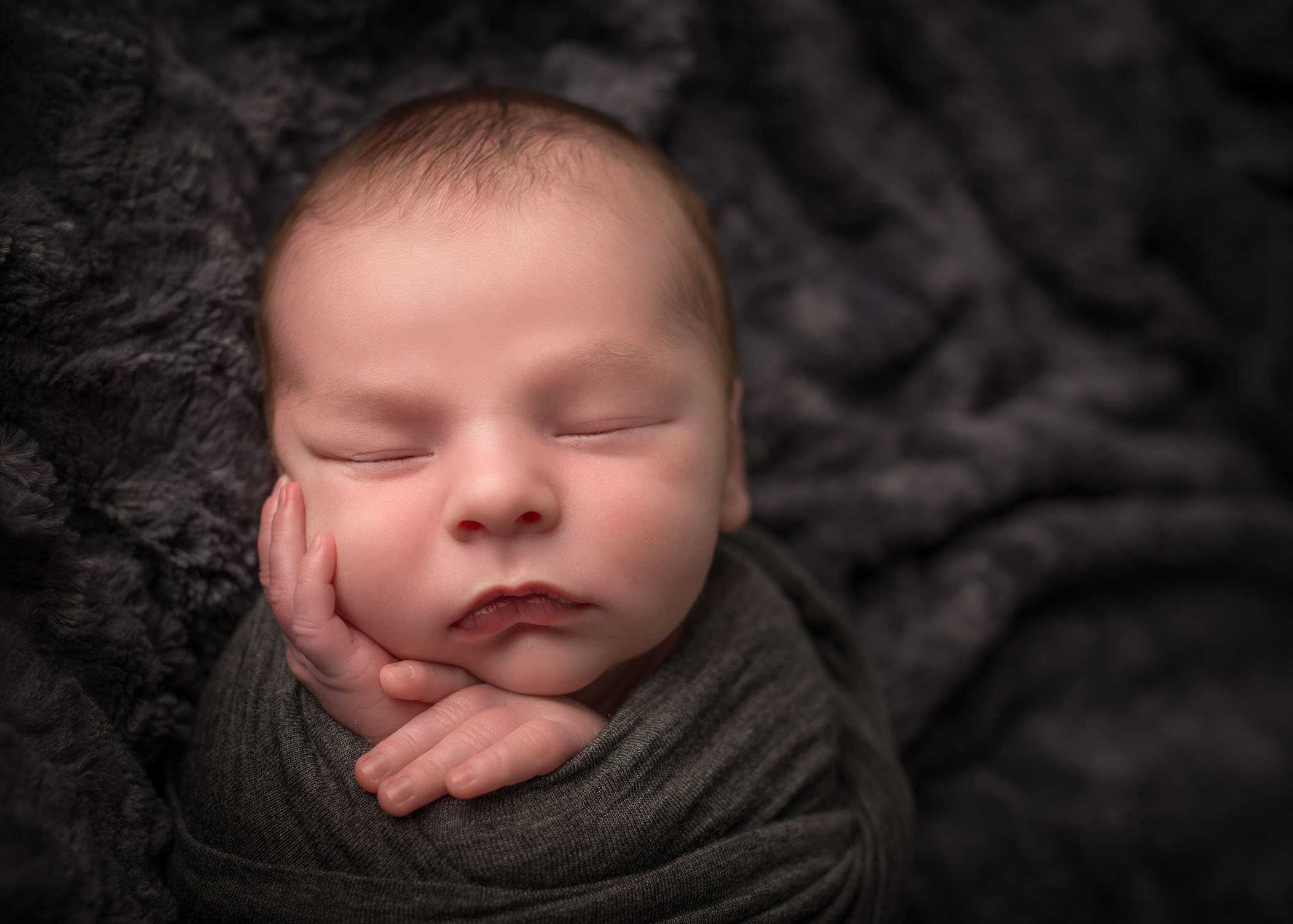 newborn boy sleeping with hand on face and perfect pout lips