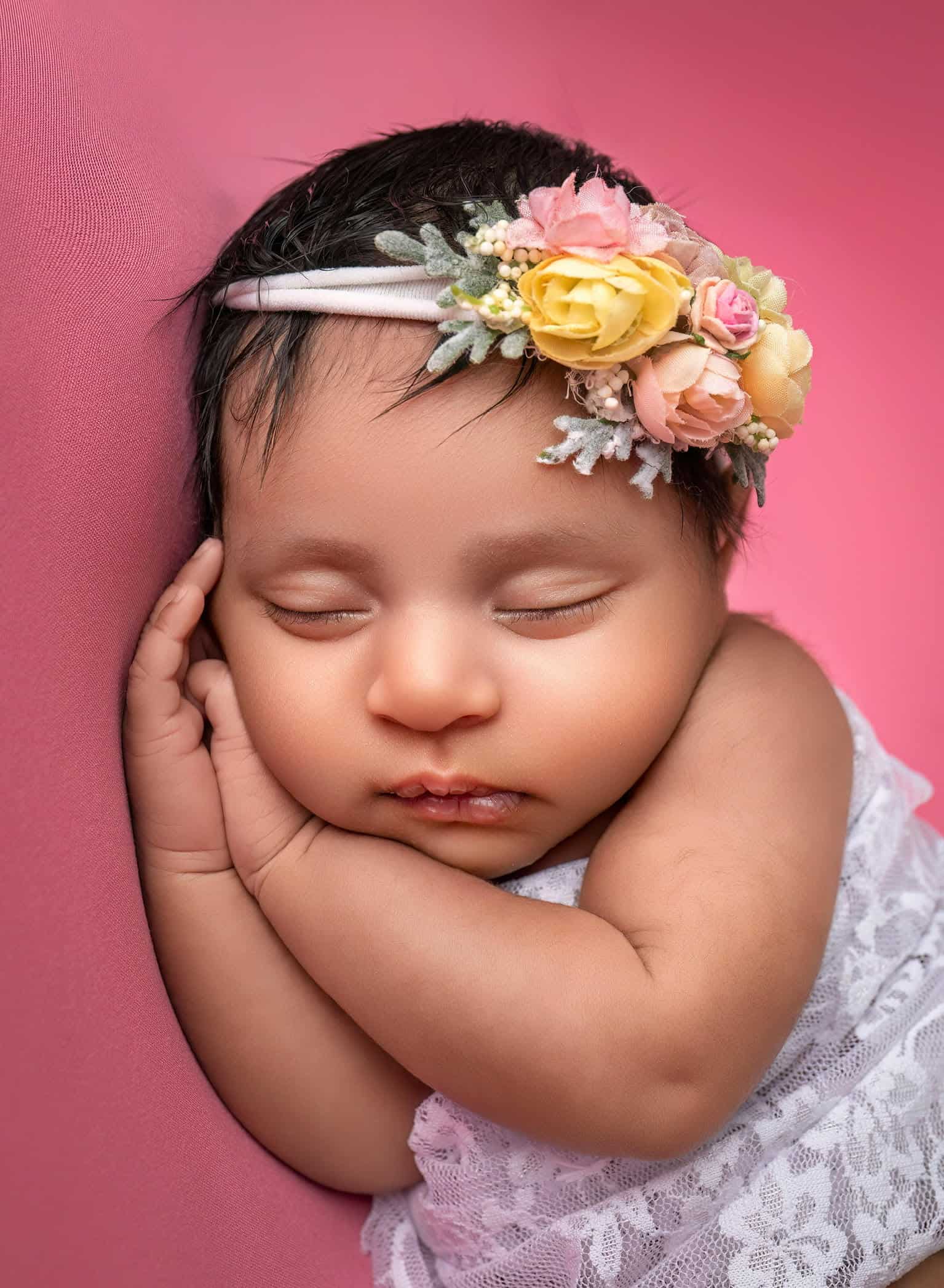 newborn baby girl wrapped in lace peacefully sleeping on her hands