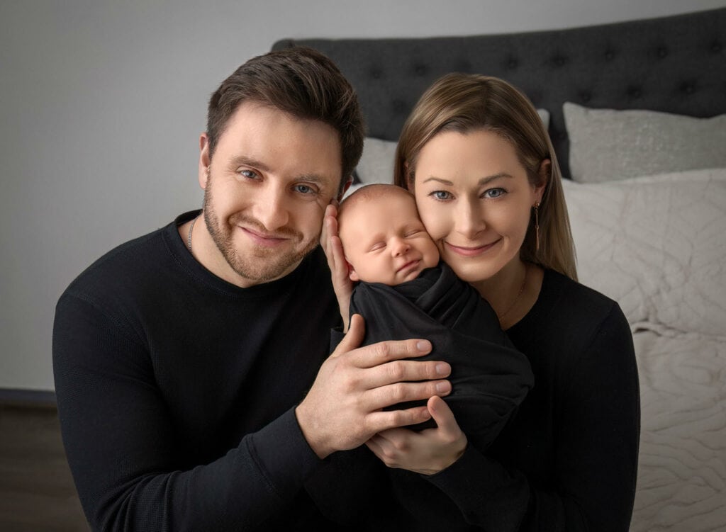 newborn photos what to wear Luxury newborn photographer Connecticut Family portrait with parents snuggling their newborn close