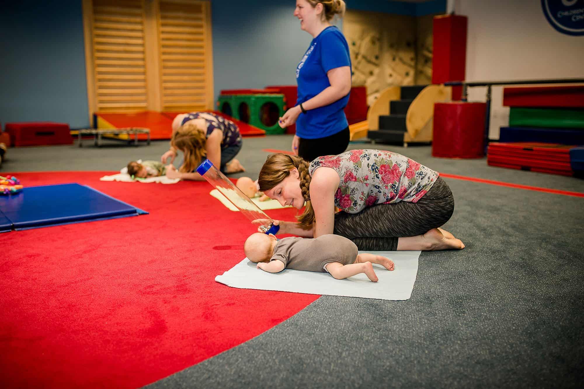 Mom showing baby contained jingle bells for playtime at My Gym Glastonbury