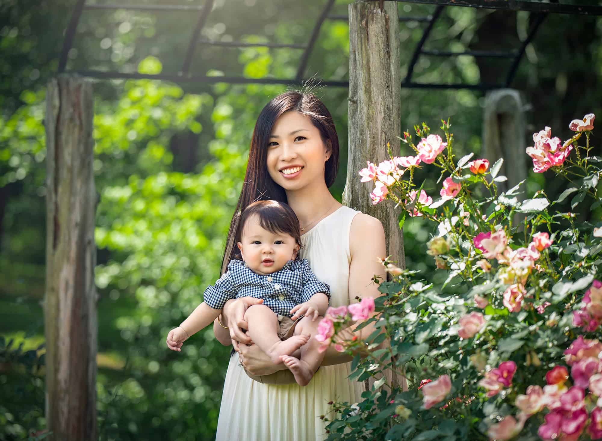 Springtime 6-month Baby Photos mom holding toddler boy outside next to pink flower bush