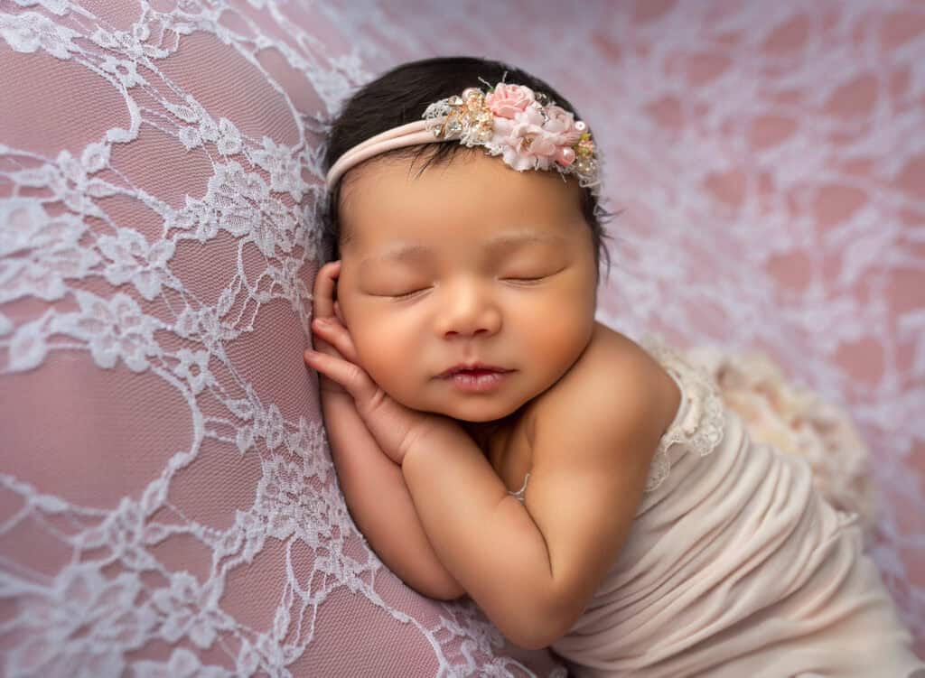 newborn infant photos newborn baby girl asleep resting head on her hands on peach lace backdrop