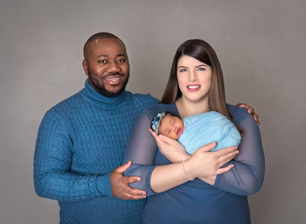 New parents smiling with mom cradling baby girl