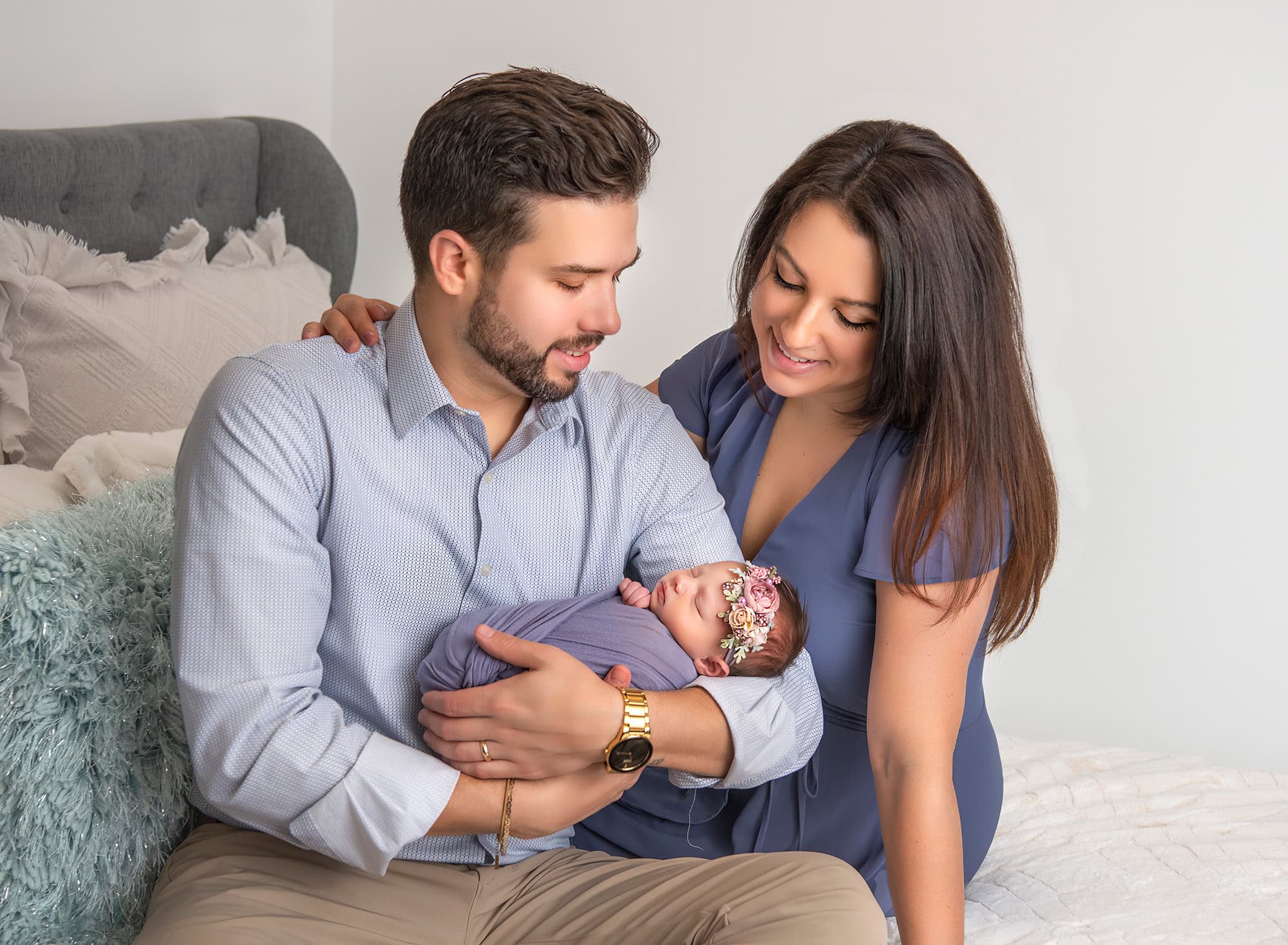 maternity and newborn photography Dad holding baby Brooklyn on the bed, with Mom looking over his shoulder.