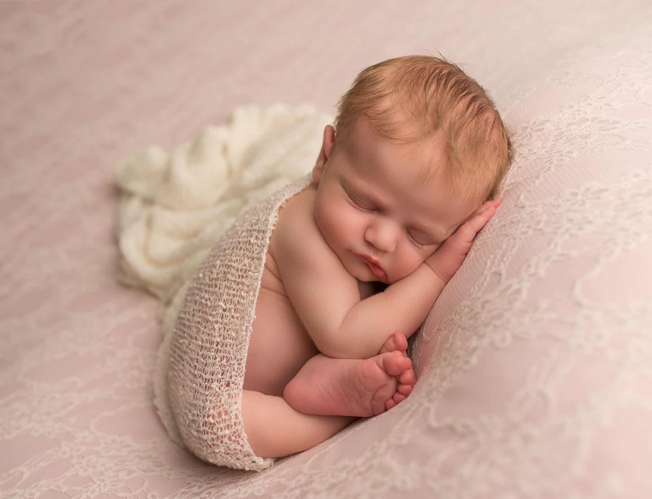 newborn in womb position with cream wrap on