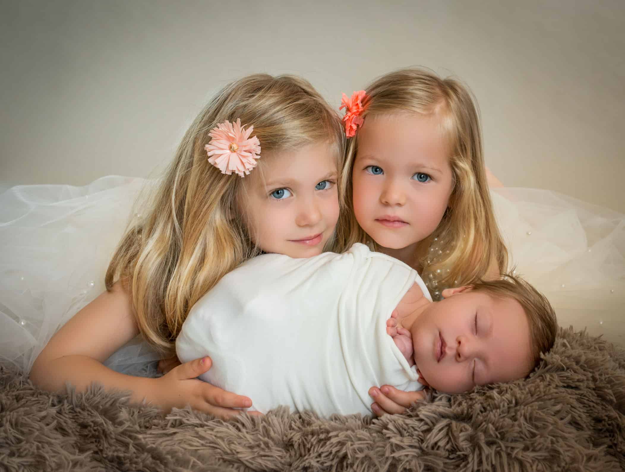 toddler girls lying down with newborn brother