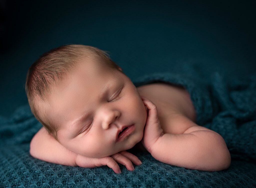 newborn baby boy asleep on teal blankets