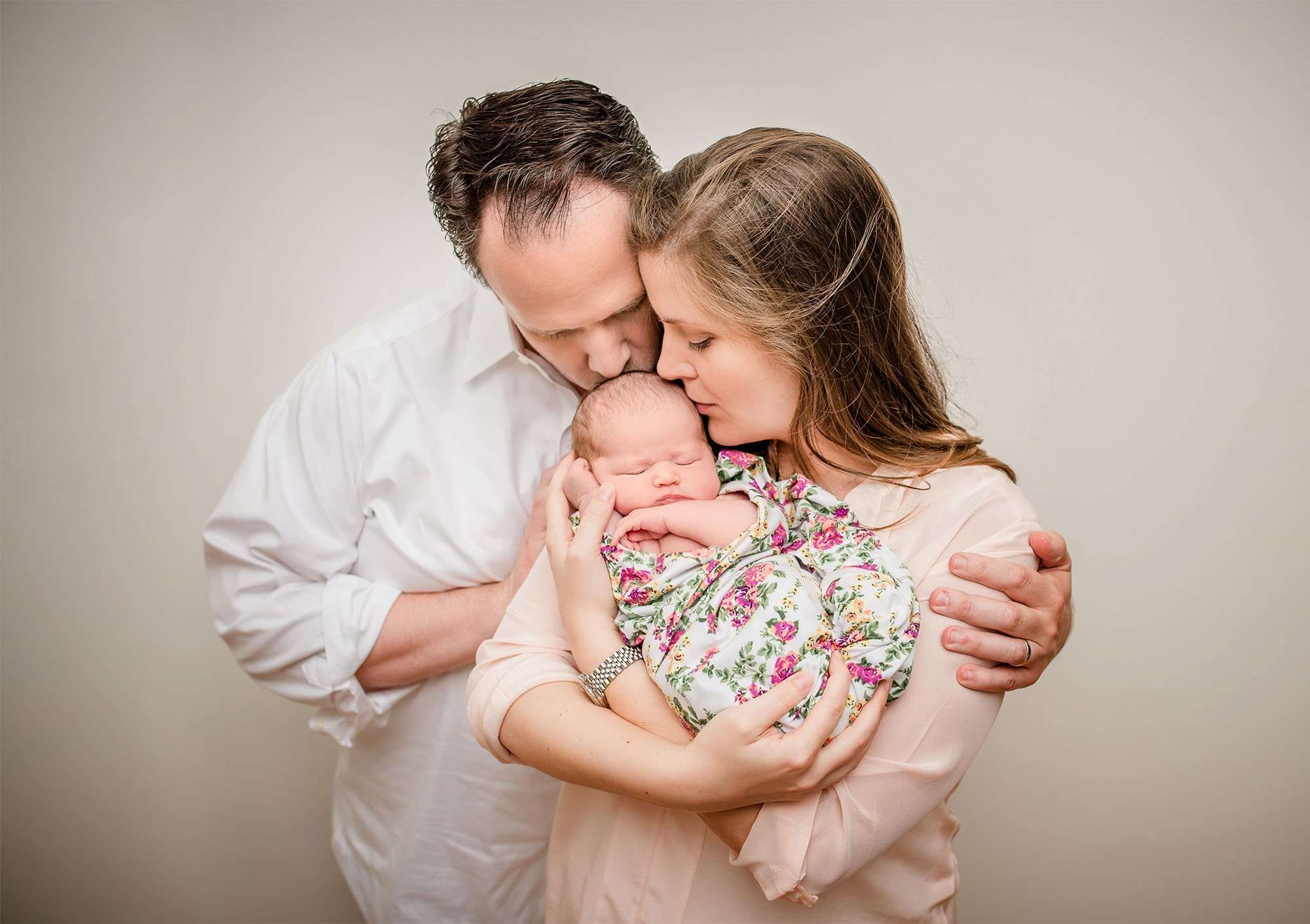 parents holding and kissing newborn baby girl One Big Happy Photo