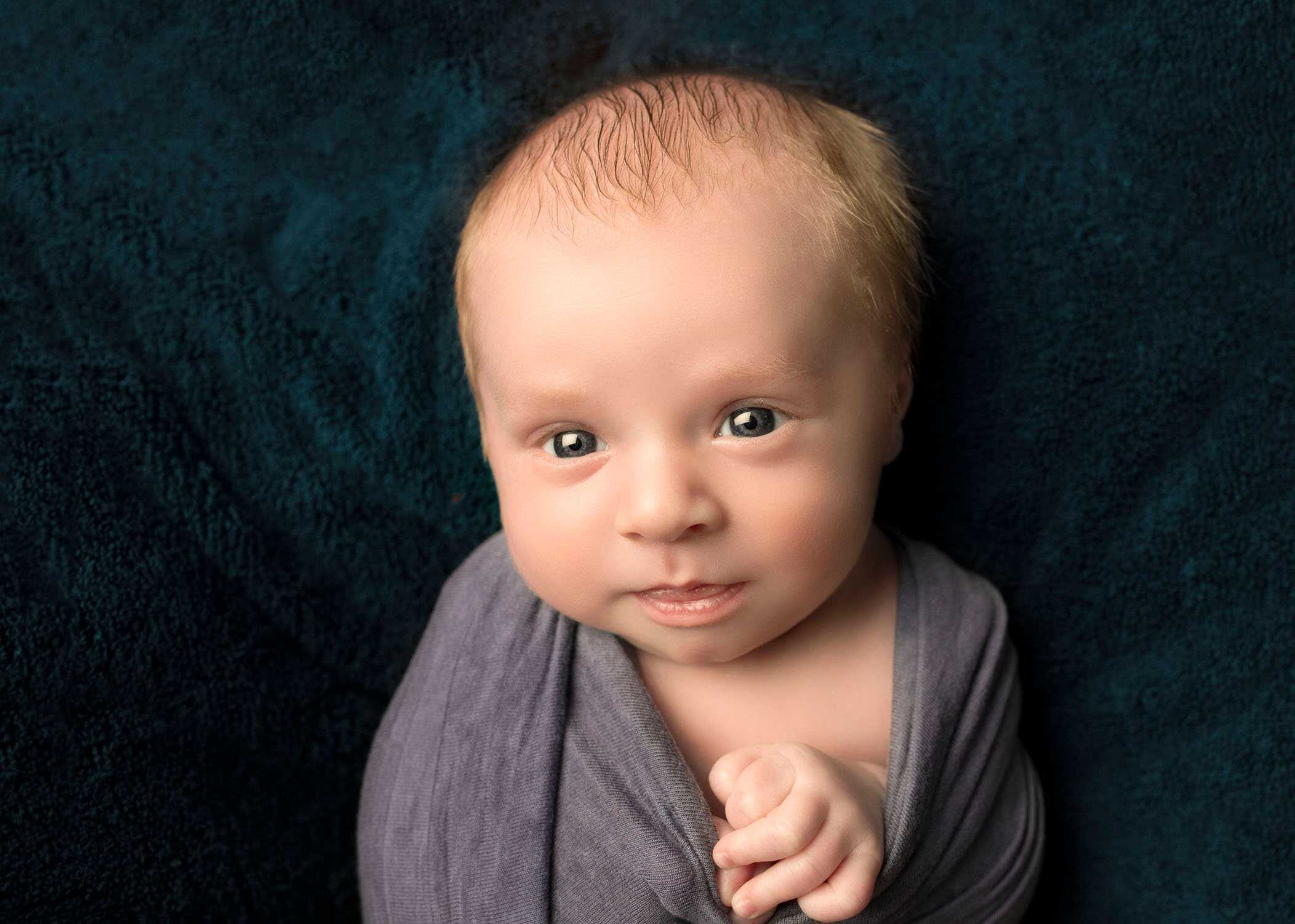 newborn boy looking at camera wrapped up